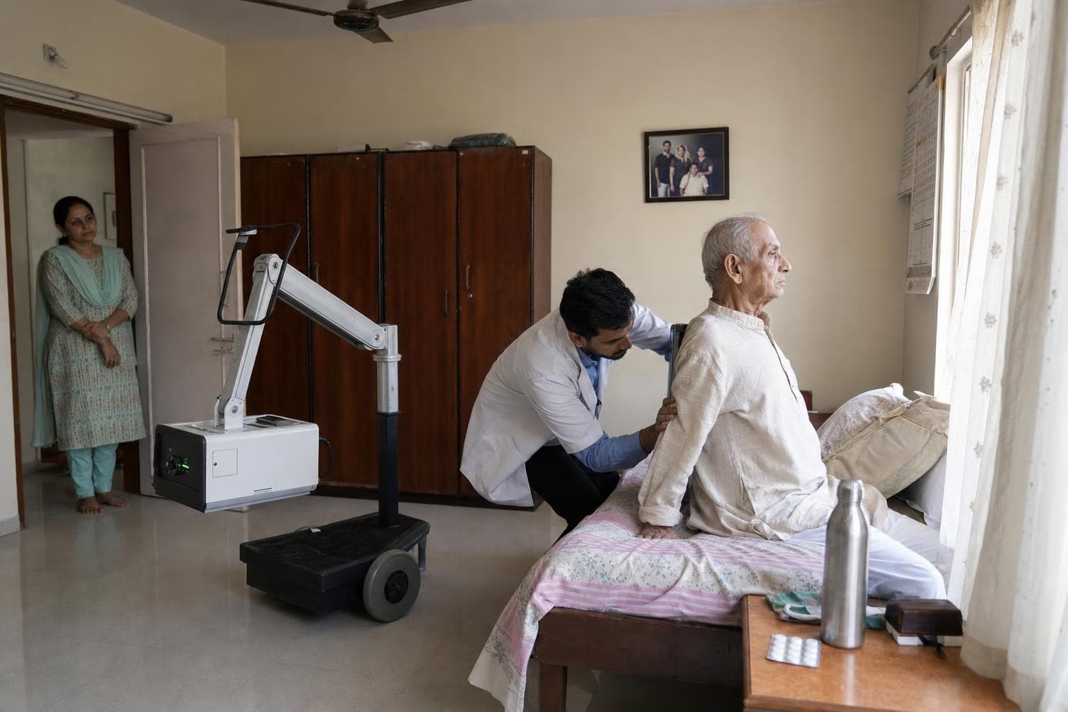 A Healkin technician positioning a portable digital X-ray for a patient in his own bed